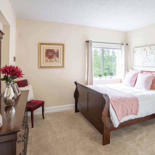 A resident bedroom with a made bed and large window