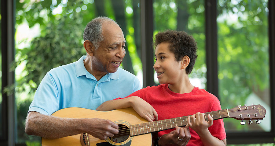 Grandfather and grandson playing guitar.