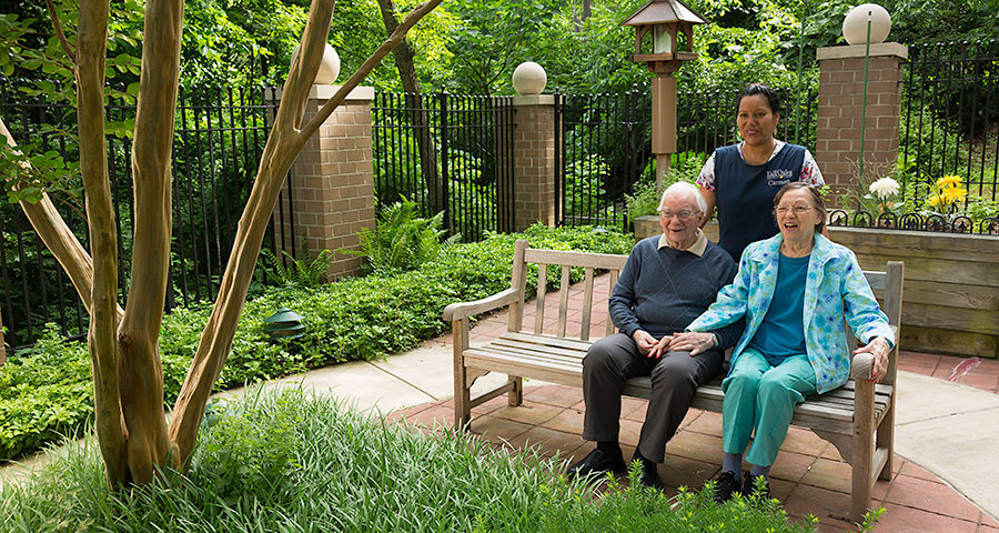 Team member with residents in the enclosed memory care courtyard.